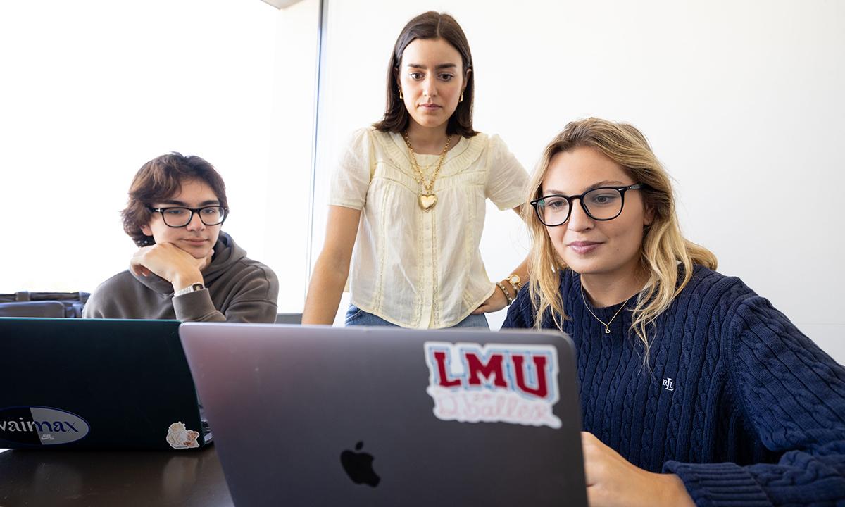 Three students looking at a laptop